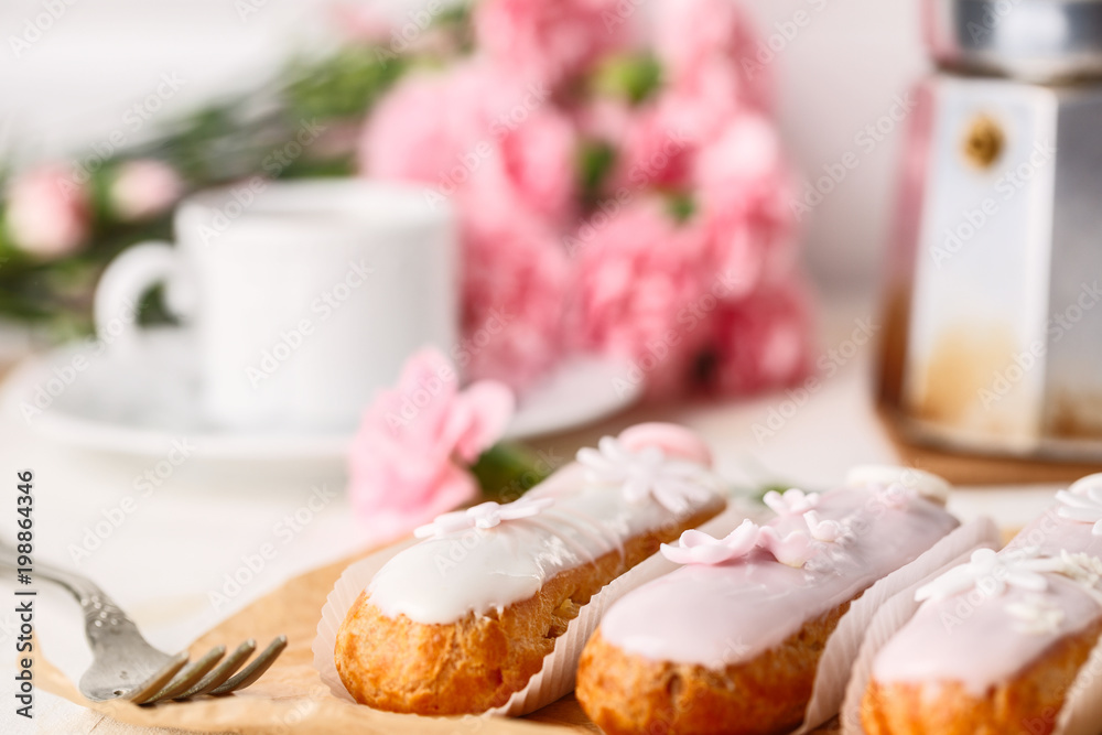 Traditional french eclairs on white table with pink flower. Copyspace