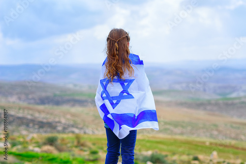 Canvas Print Little patriot jewish girl standing  and enjoying with the flag of Israel on blue sky background