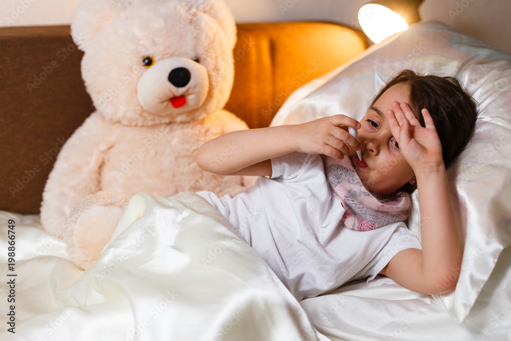 Sick girl lying in bed with a thermometer in mouth and touch his forehead Sick girl lying in bed with a thermometer in mouth and touch his forehead