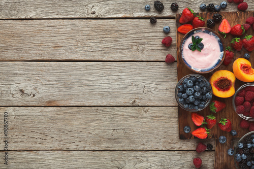 Yogurt, fruits and berries on rustic wood, top view