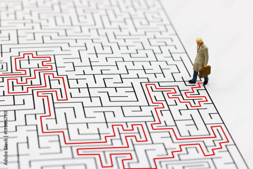 Miniature people: Businessman standing on center of maze. Concepts of finding a solution, problem solving and challenge. Miniature people: Businessman standing on center of maze. Concepts of finding a solution, problem solving and challenge.