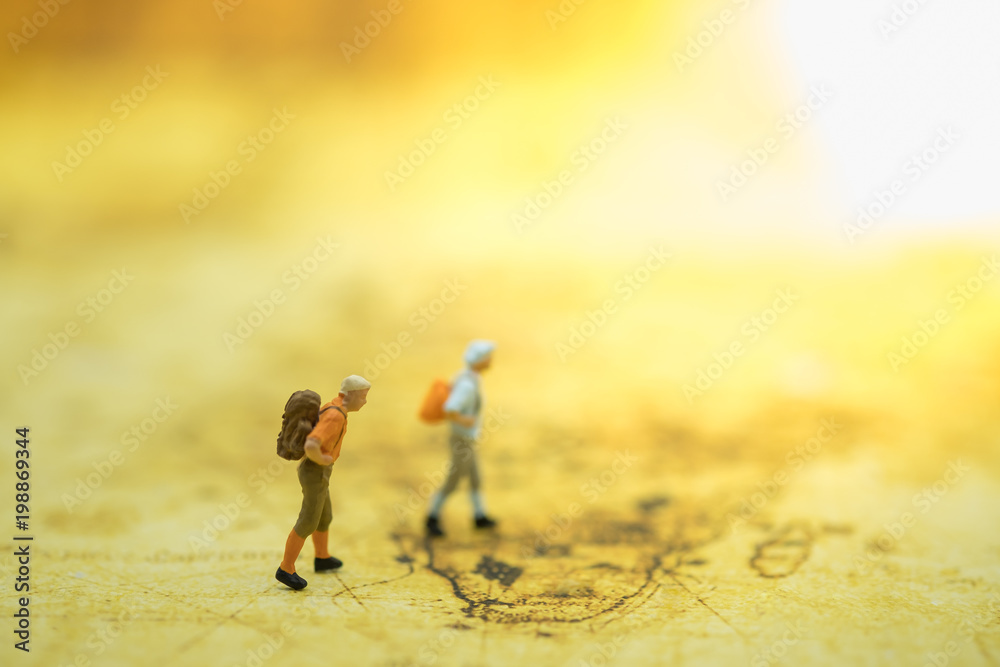 Fototapeta premium Travel Concept. Two traveler miniature figures with backpack walking on world map.