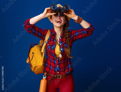 tourist woman on blue background looking up through binoculars