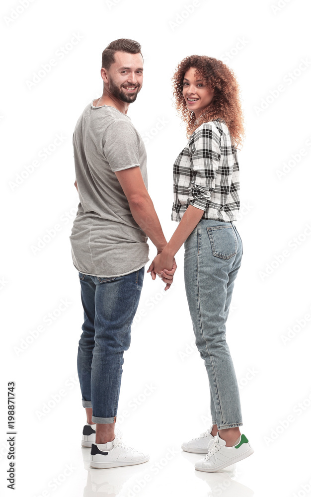 Rear view of happy couple holding hands and looking at camera Rear view of happy couple holding hands and looking at camera