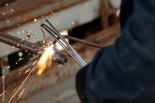 Картината върху платно hands of man, using argon welding to weld metal pipe, sparks flying in all direc