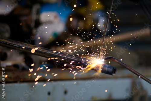 hands of man, using argon gas welding to weld metal pipe, sparks flying in all directions