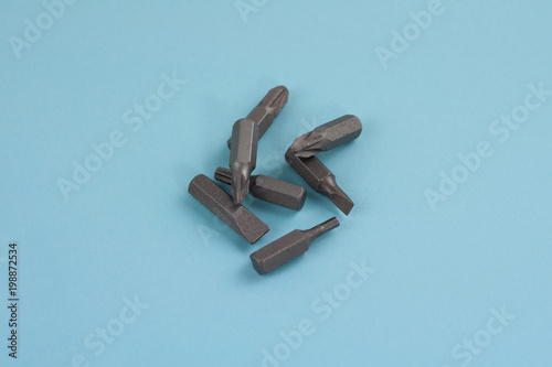 Heap of metal bits for screwdriver in form of triangle on blue background