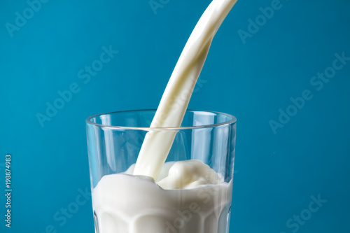 Fluffy milk in a glass on a blue background