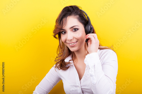 Beautiful woman working as a telemarketer wearing a headset on yellow background