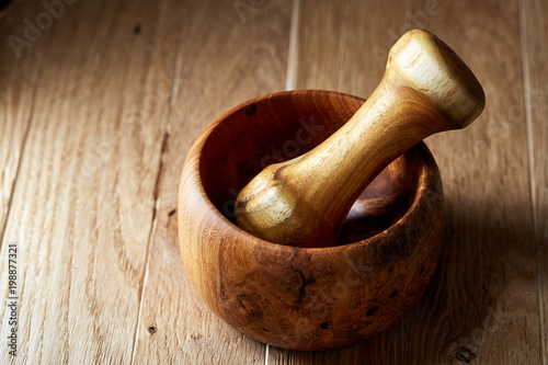 Top view close-up picture of wooden pestle and mortar on brown rustic wooden background, shallow depth of field