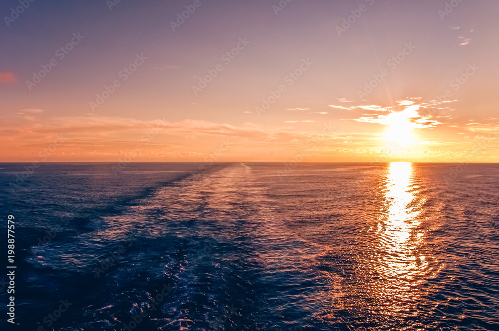 Naklejka premium Sunset at sea with waterway of a cruise ship