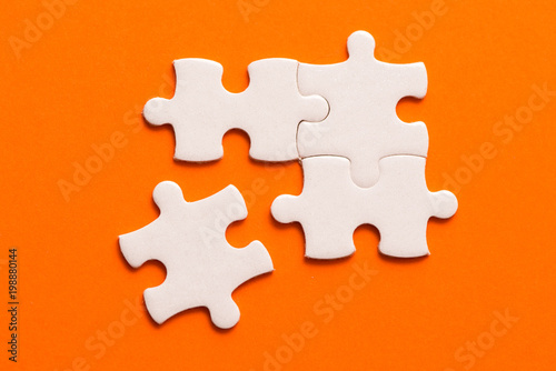 Four white details of puzzle on orange background