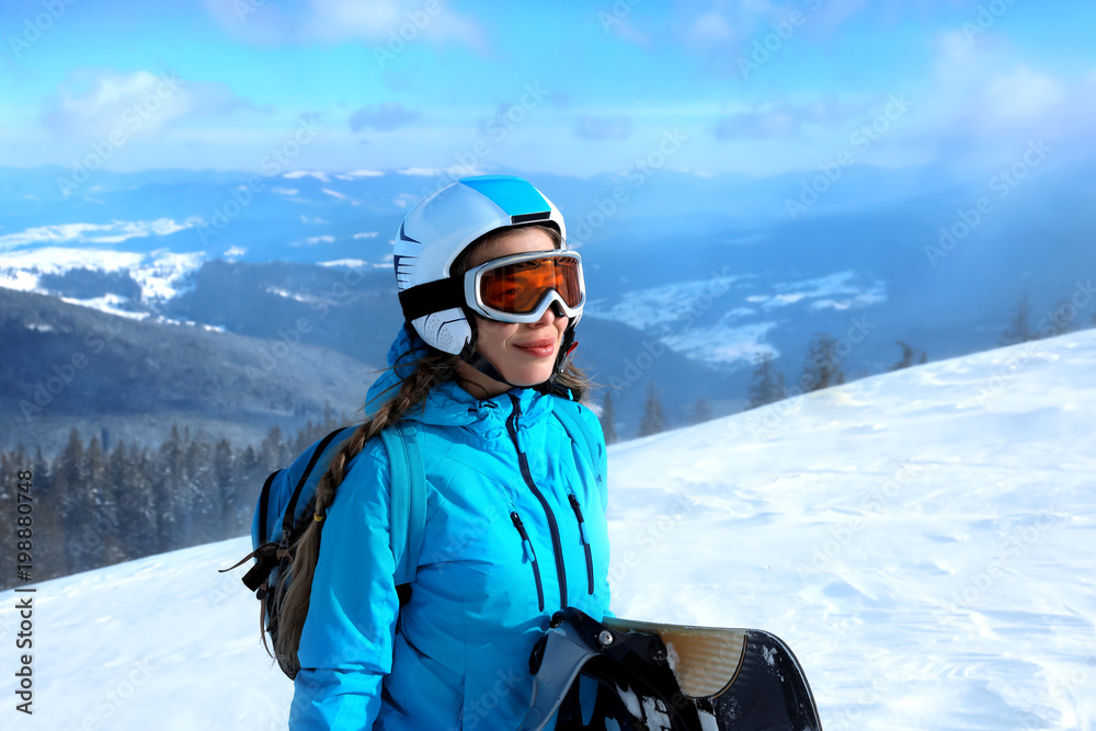 Female snowboarder on ski piste at snowy resort. Winter vacation