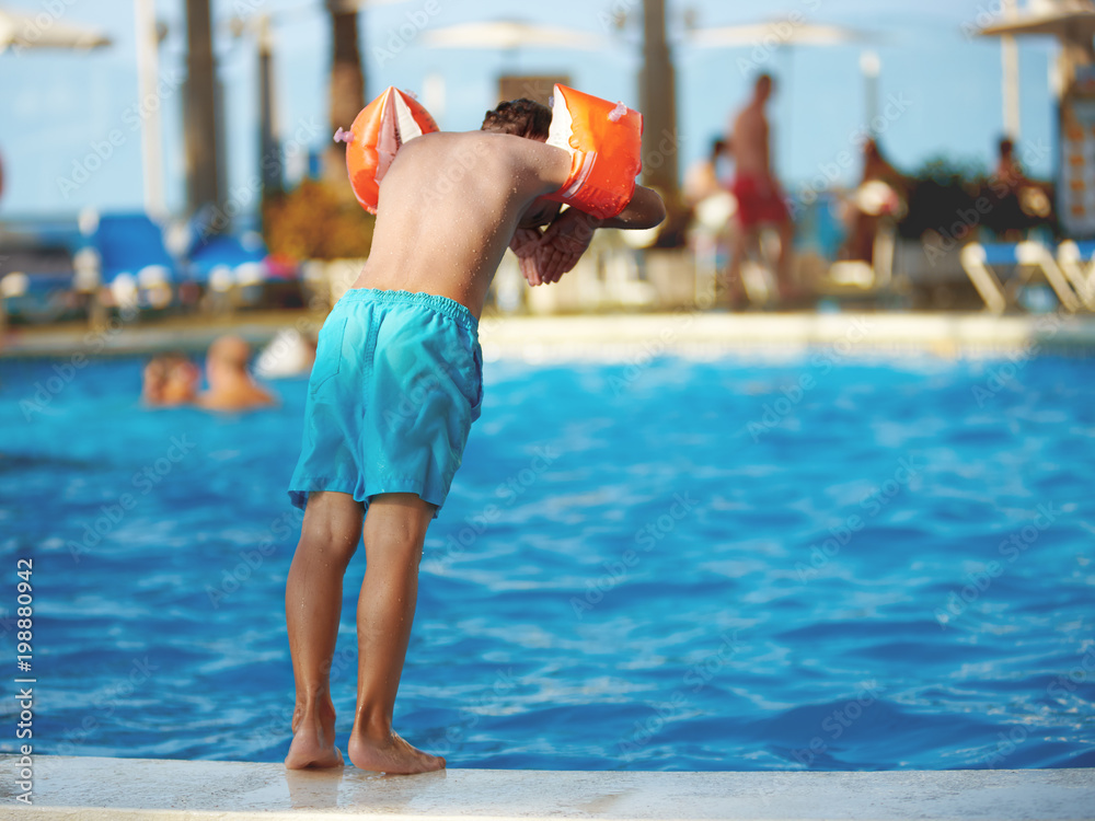 Caucasian boy having fun jumping into the pool.