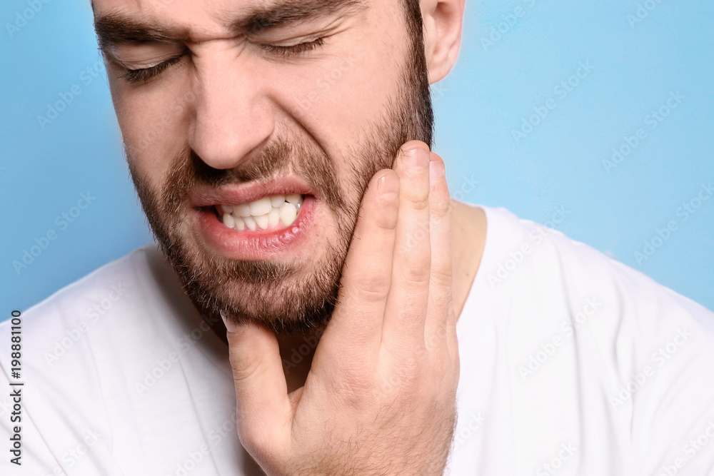 Obraz premium Young man suffering from toothache on grey background