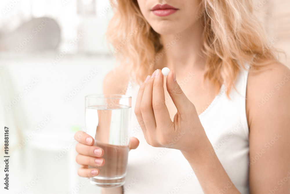 Young woman with pill and glass of water indoors Young woman with pill and glass of water indoors