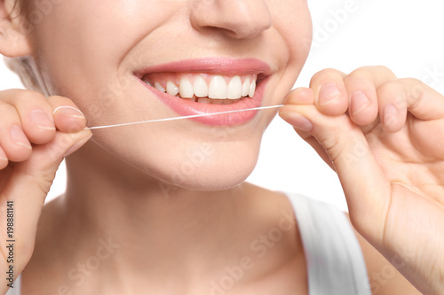 Young woman flossing her teeth on white background  closeup