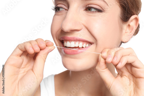 Young woman flossing her teeth on white background