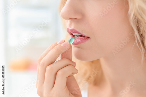 Young woman taking pill indoors