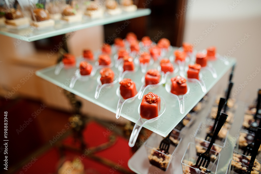Set of salty small appetizers in a red glaze decorated with sun-dried tomato Set of salty small appetizers in a red glaze decorated with sun-dried tomato