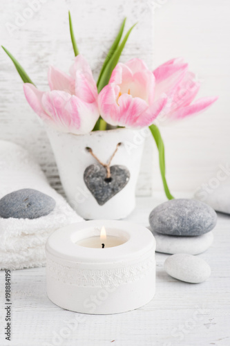 Pink tulips, pebbles and lit candle