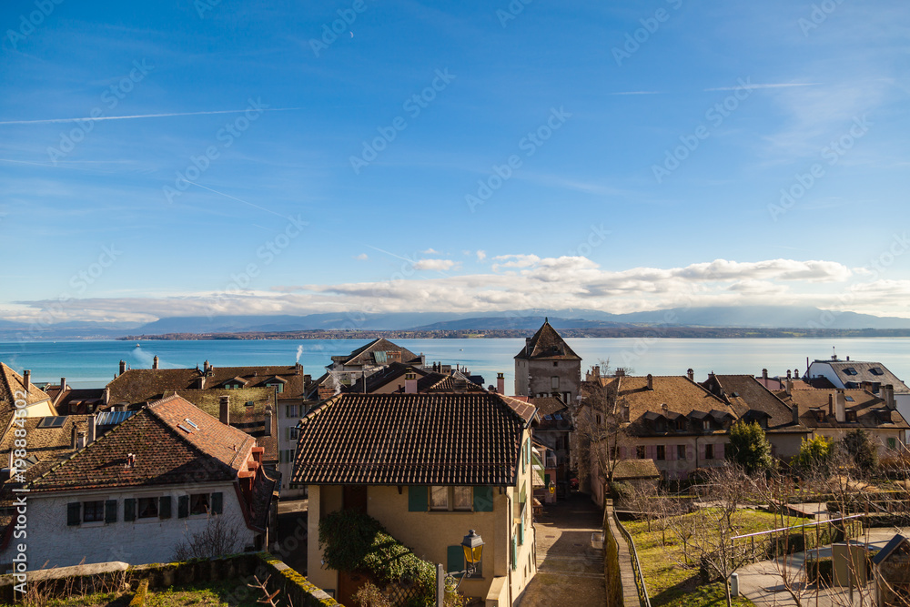 Beautiful view of the roofs in the old city Nyon and blue Leman lake. Blue sky and clouds. Switzerland