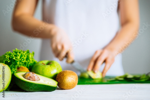green fruits on front. woman cut fruits on background. healthy f