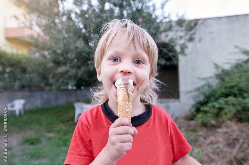 Cute boy eating ice-cream during walk in tropical resort Cute boy eating ice-cream during walk in tropical resort