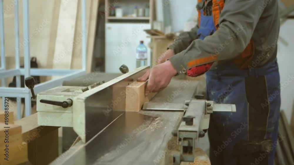 The carpenter scribes the board on a white jointing machine The carpenter scribes the board on a white jointing machine