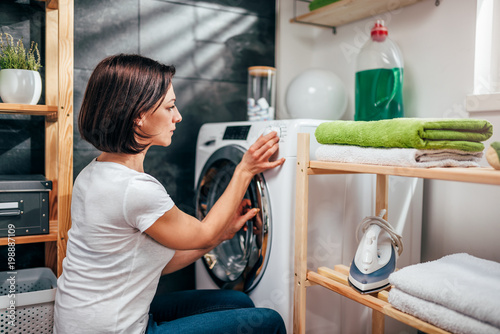 Woman choosing program on washing machine photo