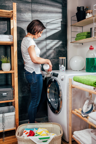 Women pouring fabric softener into a washing machine