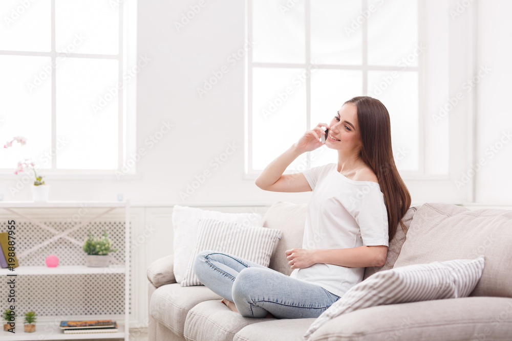 Happy young woman sitting on sofa with cell phone Happy young woman sitting on sofa with cell phone