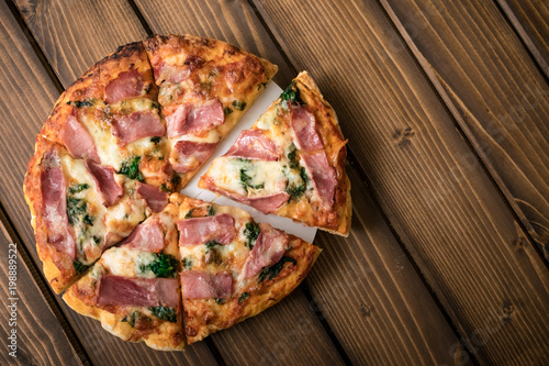 Homemade pizza with spinach, smoked ham. wooden background, copy space.