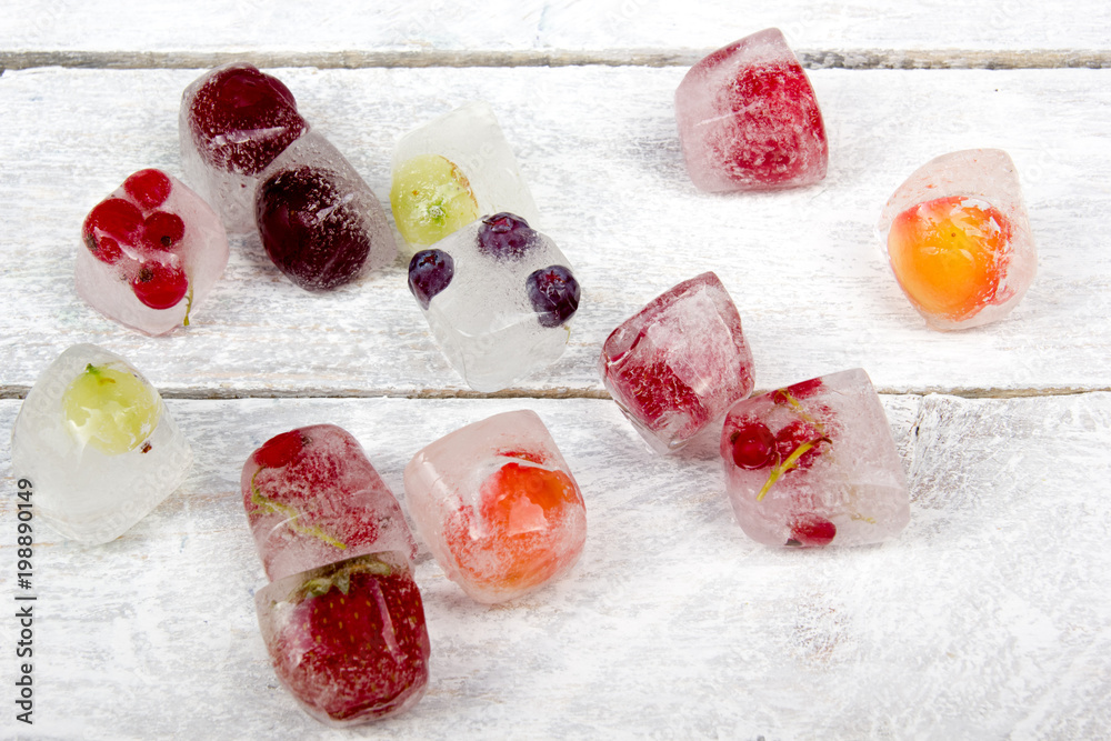 Berries frozen in ice cubes with mint on wooden table background. Berries frozen in ice cubes with mint on wooden table background.