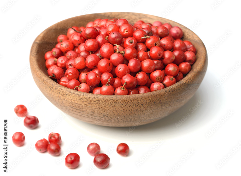 dried pink peppercorns in the wooden plate, isolated on white dried pink peppercorns in the wooden plate, isolated on white