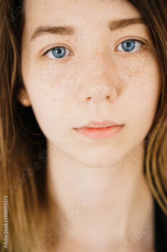 close-up portrait of a young beautiful girl with blue eyes and freckles. Natural beauty and emotion.