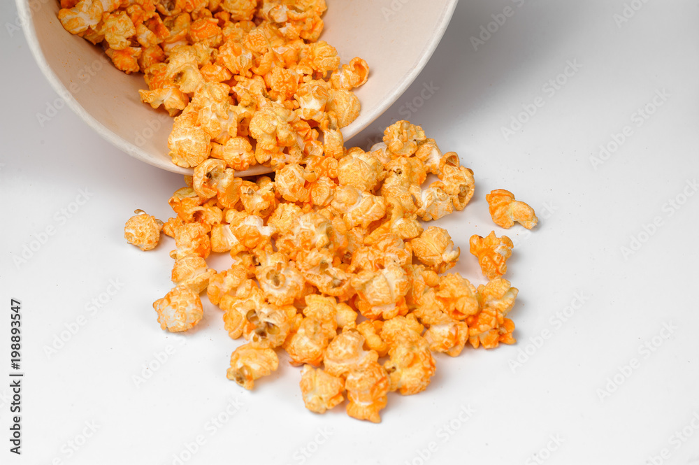 yellow delicious roasted popcorn scattered from a bucket on a white background