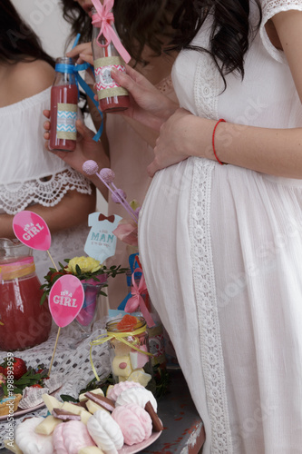 Group of women at a baby shower enjoying food and drink. Pregnant woman celebrating baby shower with female friends at home.