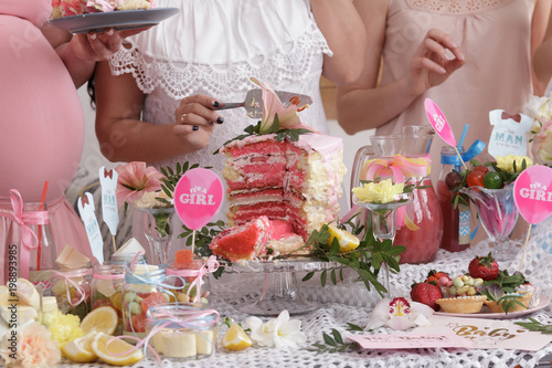 Group of women at a baby shower enjoying food and drink. Pregnant woman celebrating baby shower with female friends at home.