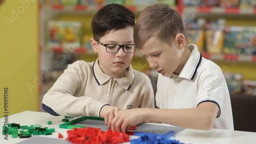 Two boys erect buildings from a children's plastic designer photo