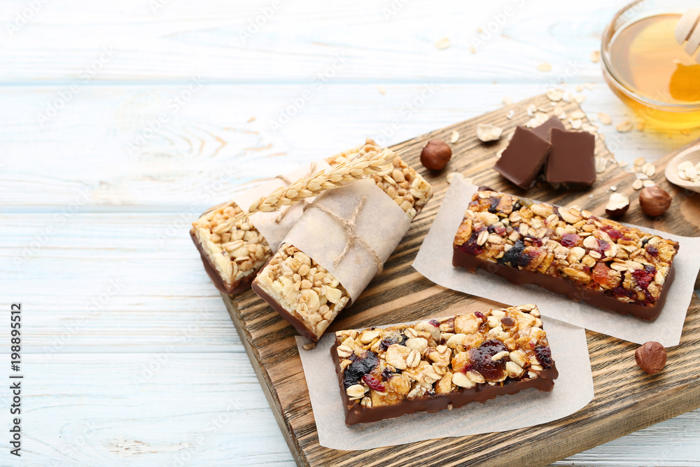 Tasty granola bars with nuts and chocolate pieces on wooden table