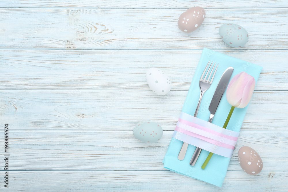 Kitchen cutlery with easter eggs and tulip flower on wooden table Kitchen cutlery with easter eggs and tulip flower on wooden table