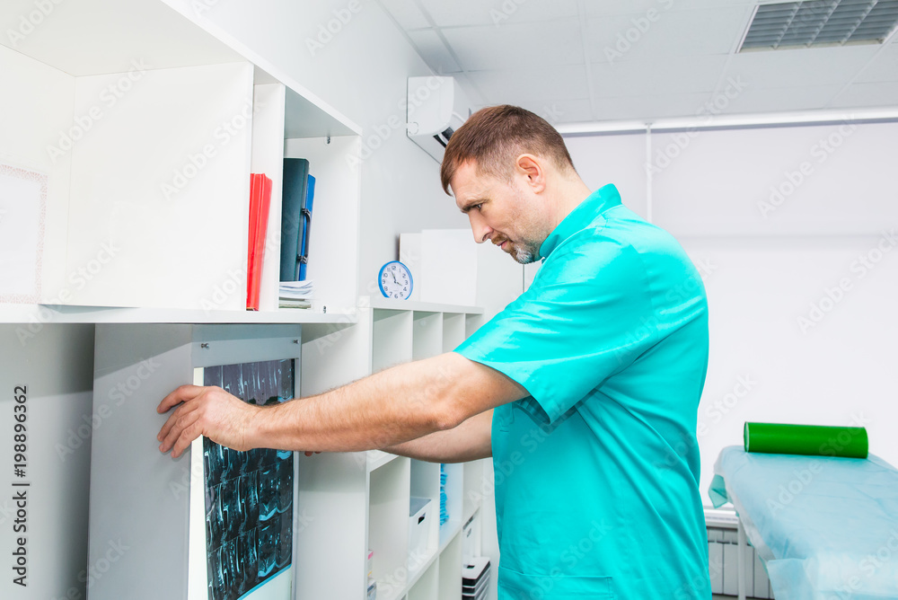 Male doctor looking at x-ray image of cervical spine in his office. Osteopathy, chiropractic, physiotherapy. Healthcare, roentgen, people and medicine concept. Selective focus, space for text.