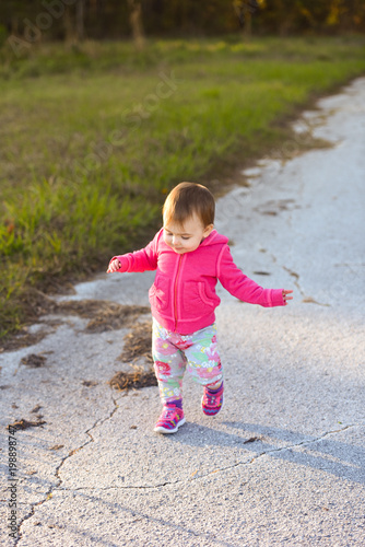 A little girl is walking along the path at a park © Tanya
