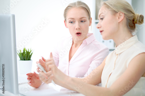 Two business ladies or colleagues discussing something in office background