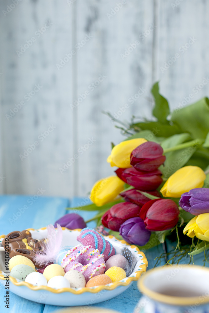 Easter sweets for the holiday. Spring. Bright colors on coffee mugs. A bouquet of fresh tulips. Free space for text