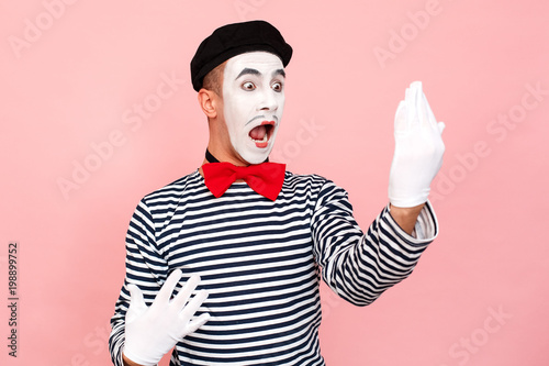 Street artist in a striped sweater, white gloves looking mirror, scream photo