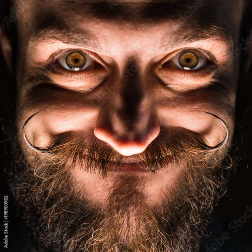 Inventor Hipster with Beard and Mustages in the Dark Room. Smiling Trickster.