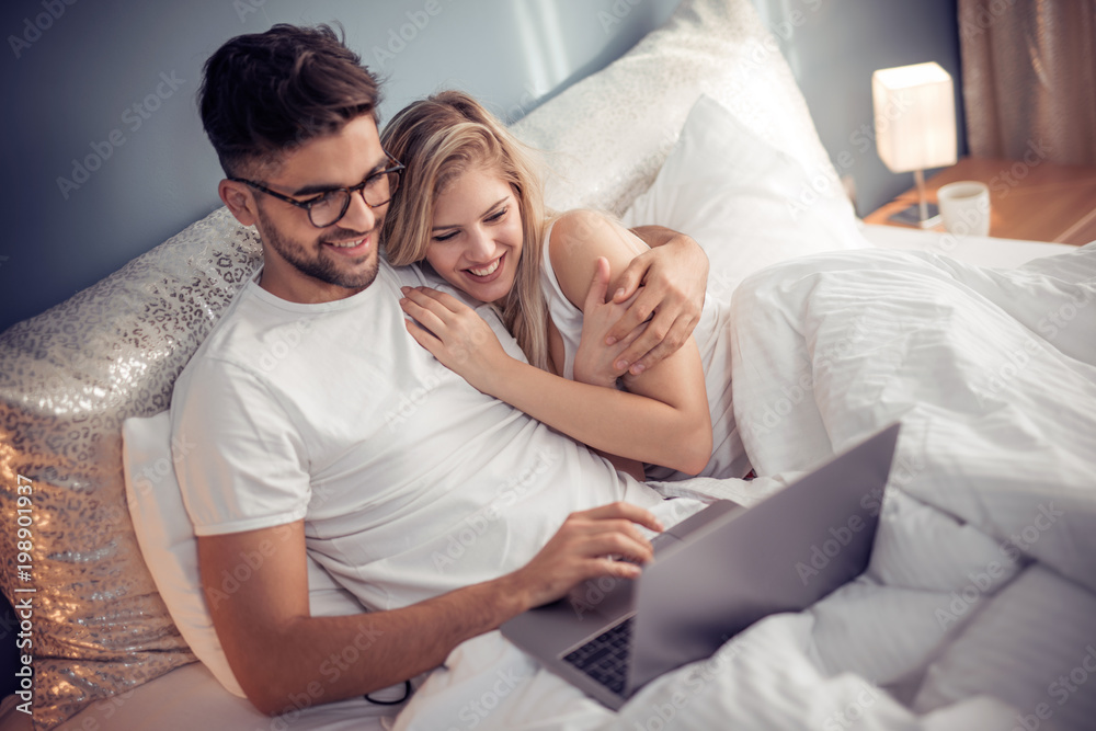 Young couple with laptop in the bed Young couple with laptop in the bed