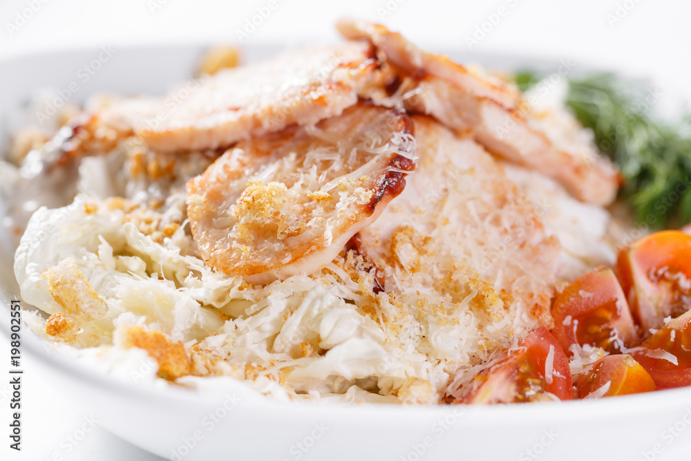 Caesar Salad with chicken . Comprises iceberg lettuce Leaf and croutons dressed with parmesan cheese. White light background Caesar Salad with chicken . Comprises iceberg lettuce Leaf and croutons dressed with parmesan cheese. White light background